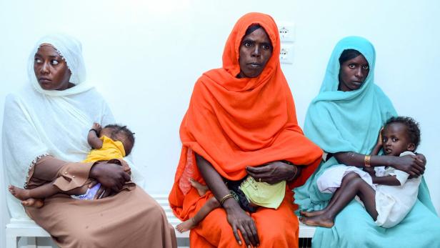 Drei Mütter mit ihren Kindern sitzen in einem Raum im Sudan.