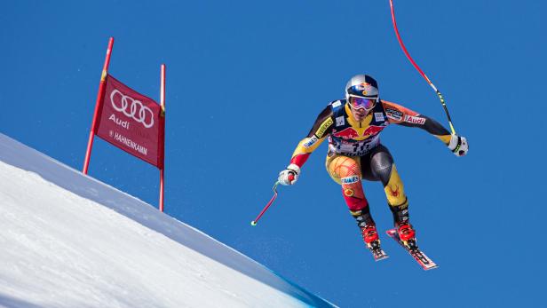 Ein Skirennläufer springt während eines Rennens auf der Hahnenkamm-Strecke.