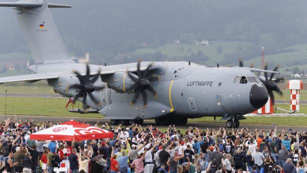Großes graues Luftwaffe-Transportflugzeug rollt an einer jubelnden Menschenmenge vorbei.