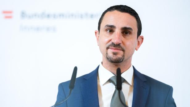 Ein Mann in einem blauen Anzug steht vor einem Mikrofon.