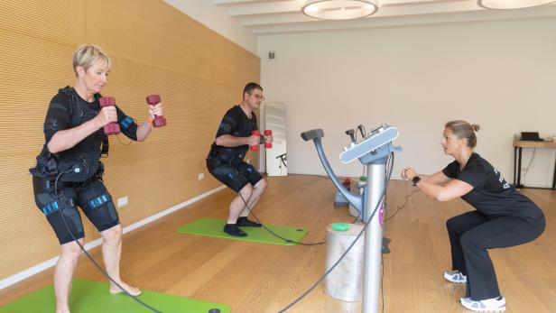 Das Bild zeigt Dagmar Paß und Rudolf Grubauer beim medizinischen EMS-Training mit der Trainerin Julia Codet, die rechts im Bild zu sehen ist:  erfolgreiche Therapie der Rückenschmerzen.