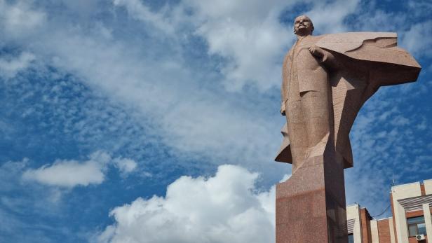 Eine aus Stein gehauene Lenin-Statue vor einem bewölkten Himmel