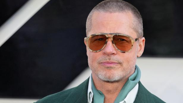 Brad Pitt trägt eine Sonnenbrille und einen grünen Anzug mit einem hellblauen Schal.