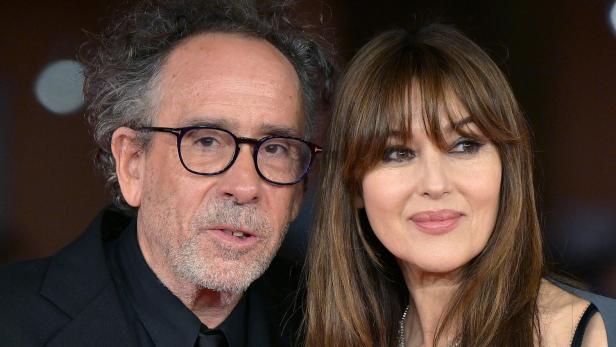 Tim Burton und Monica Bellucci posieren nebeneinander auf einem roten Teppich.