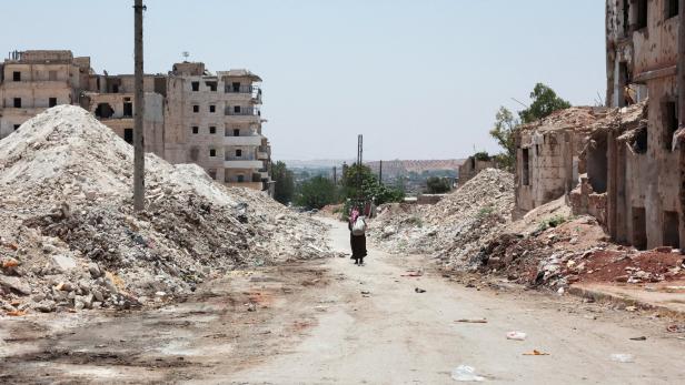 FILE PHOTO: A man walks through the destruction in the city of Aleppo