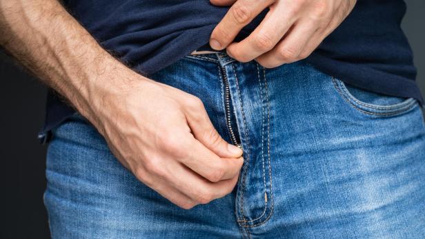 Mann öffnet Zippverschluss seiner Jeans