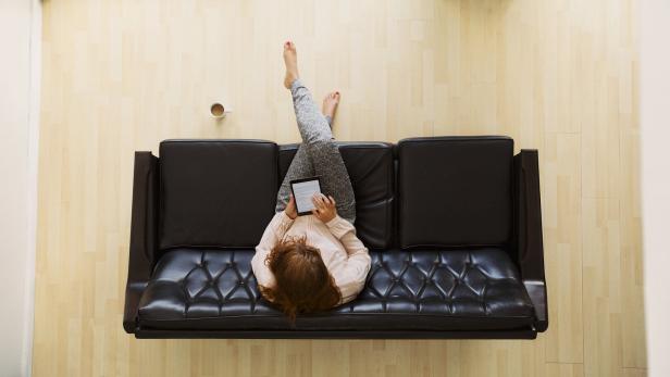 Young woman sitting on a sofa with digital tablet