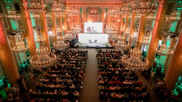 Ein großer Saal der Wiener Hofburg mit Lustern und vielen Menschen