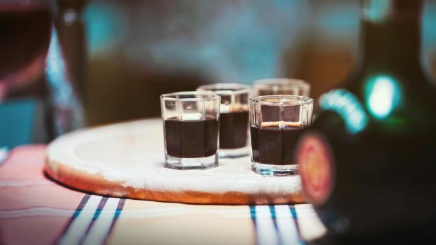 Eine Flasche Schnaps mit vier Gläsern auf einem Tisch, bereit zum Servieren.