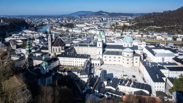 Die Salzburger Altstadt mit Dom und Festung Hohensalzburg erstreckt sich unter blauem Himmel.