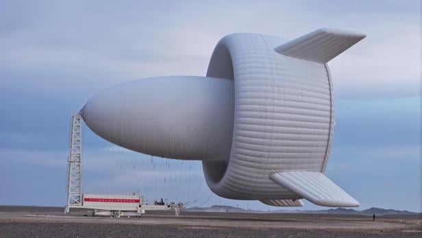 Ein großer, weißer, ungewöhnlich geformter Windrad-Prototyp steht in einer kargen Landschaft.
