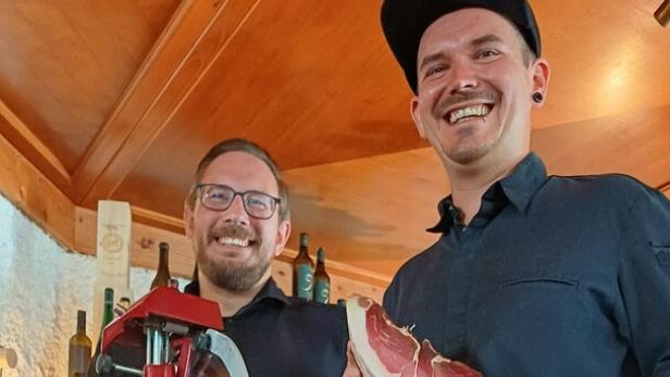 Dominik  Köppl-Pongracic, der Servicechef, und Christoph Puchegger, der Wirt, stehen bei der roten Aufschnittmaschine.  Puchegger hat einen Rauchschinken in der Hand.