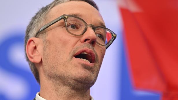 Herbert Kickl singend vor Hintergrund in Parteifarben