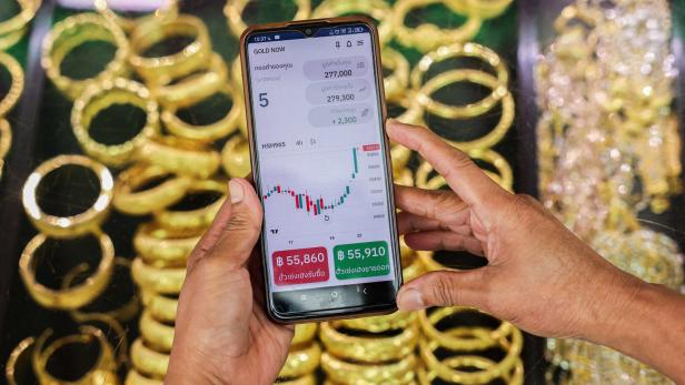 A woman uses the Gold Now app, on the day that gold surges to set a fresh record high, in Bangkok