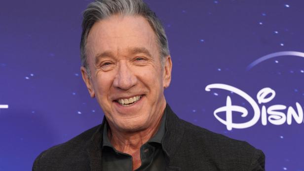 Tim Allen lächelt vor einem Hintergrund mit dem Disney+-Logo.