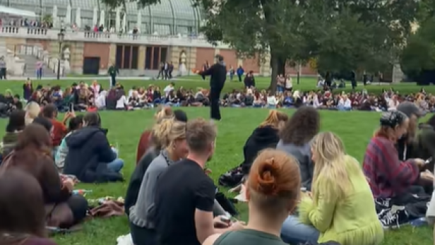 Etliche junge Menschen sitzen mit Pudding im Burggarten
