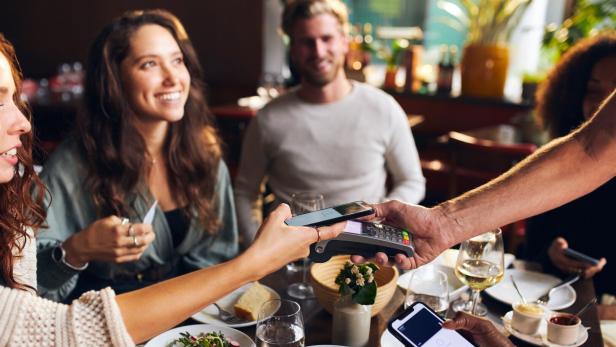 Freunden zahlen kontaktlos im Restaurant