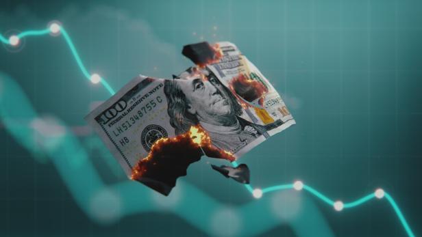 Brennender 100-Dollar-Schein vor einer Grafik mit fallenden Kursen 