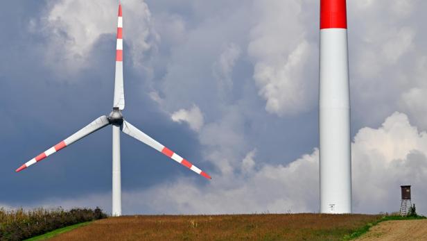 Windrad mit rot-weißen Rotorblättern auf einem Feld