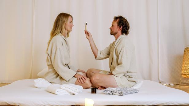 Nadin Menzer und Bernhard Semmler sitzen sich bei einem Tantra-Workshop im Schneidersitz gegenüber.