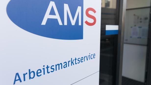 Ein Schild mit der Aufschrift „AMS Arbeitsmarktservice“ steht vor einem Eingang.