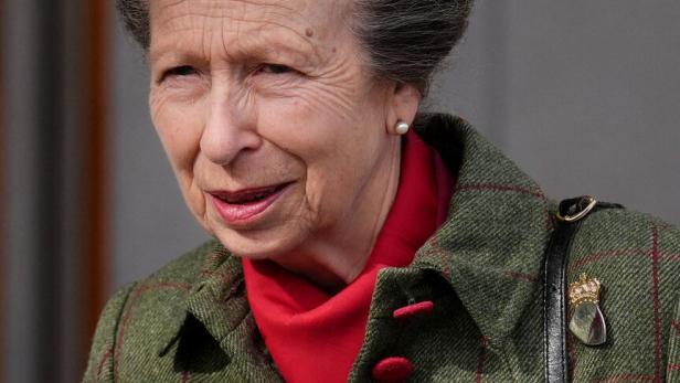 Prinzessin Anne  mit grauem Haar trägt eine karierte Jacke und ein rotes Tuch.