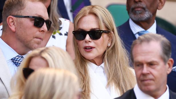 Nicole Kidman sitzt mit Sonnenbrille und weißem Blazer im Publikum.
