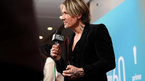 Keith Urban hält eine Auszeichnung und ein Mikrofon der Academy of Country Music Awards.