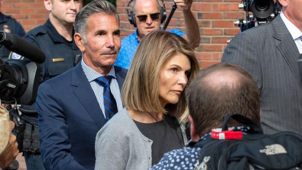 Lori Loughlin und ihr Ehemann Mossimo Giannulli umgeben von Kameras und Reportern.
