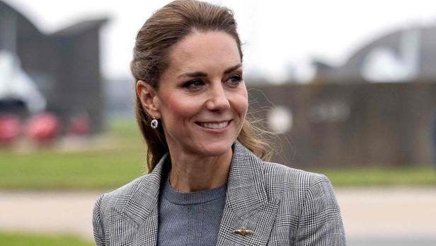 Prinzessin Kate lächelt in einem grauen Hosenanzug mit Karomuster.