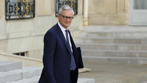 Bruno Le Maire geht eine Treppe hinunter und hält eine Mappe.