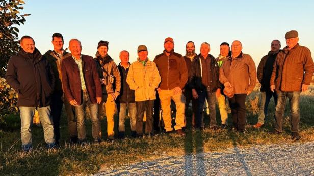 Eine Gruppe von Männern unterschiedlichen Alters steht im Freien bei Sonnenuntergang.