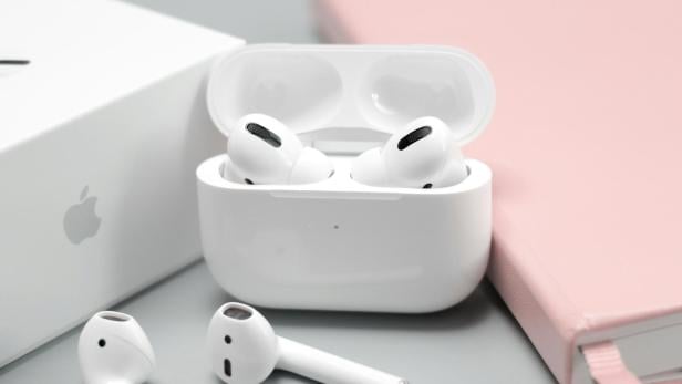 Apple AirPods liegen auf einem Tisch neben einem Notizbuch