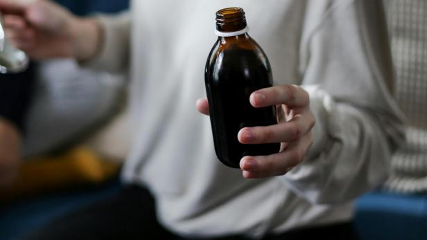 Frau hält Hustensaftflasche