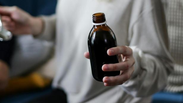 Frau hält Hustensaftflasche