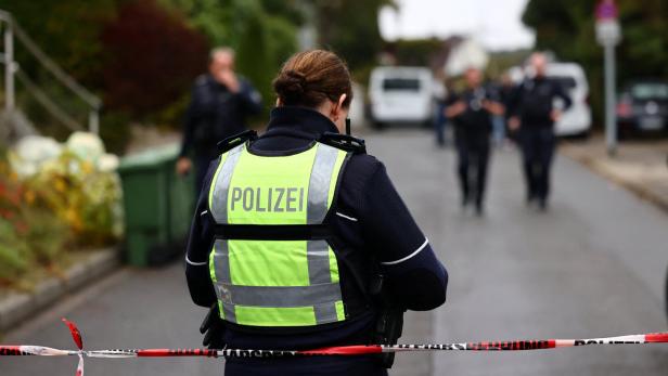 Eine Polizistin mit gelber Weste sichert einen Tatort mit rot-weißem Band ab.