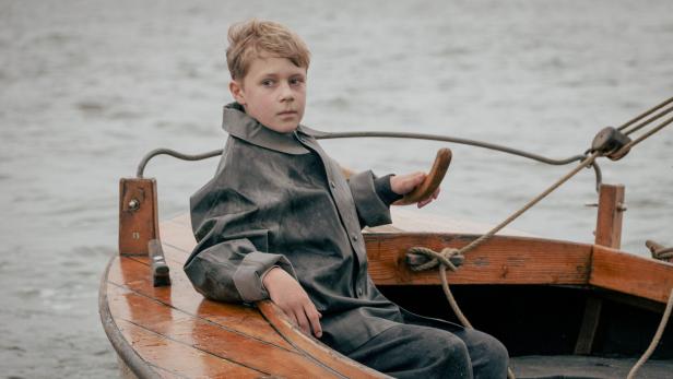 Ein zwölfjähriger Bub sitzt in einem Boot.