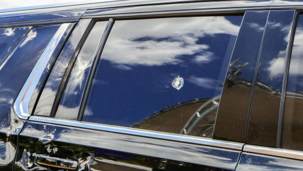 Eine schwarze Autotür mit mehreren Einschusslöchern und beschädigtem Lack.