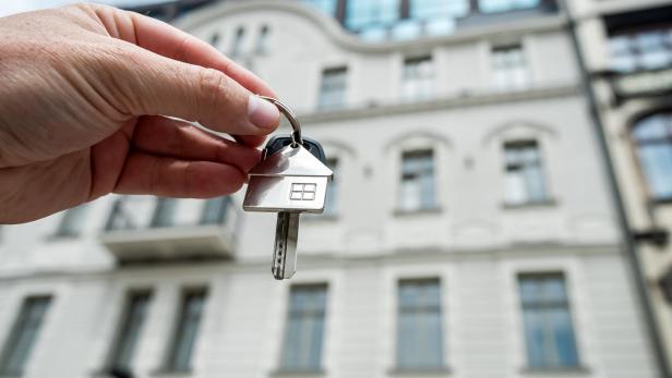 Schönes Wohnhaus im Hintergrund, im Vordergrund hält eine Hand einen Schüssel.