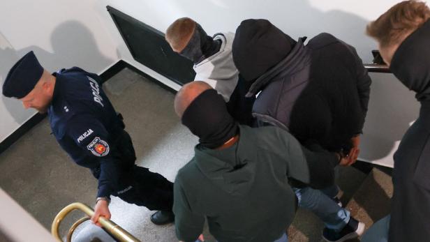 A Ukrainian diver, Volodymyr Z., walks escorted by Polish Police at the district court in Warsaw