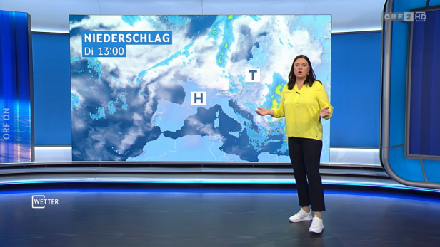 Frau in weißen Turnschuhen und mit neongelber Bluse vor Wetterkarte