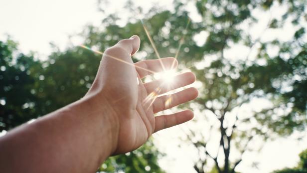 Ausgetreckte Hand, die nach der Sonne greift