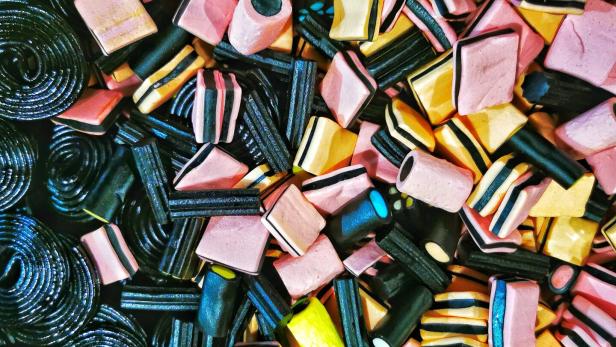 Eine bunte Mischung aus Lakritzschnecken und Lakritzkonfekt in verschiedenen Formen und Farben liegt durcheinander.