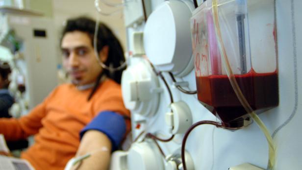 Die Zahl der Plasmaspenden ist in Österreich rückläufig. Ein Mann spendet Blutplasma, während das Blut durch Schläuche in eine Maschine und einen Behälter fließt.