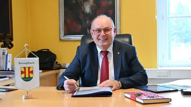 Mann in Anzug und Krawatte sitzt an einem Schreibtisch