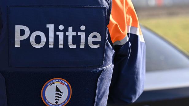 Nahaufnahme der blauen Uniform eines Polizisten mit der Aufschrift "Politie" und einem Abzeichen.