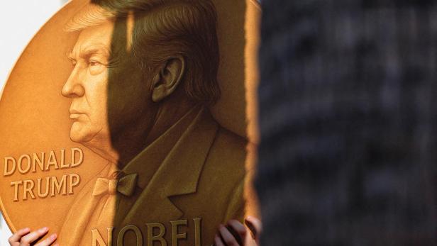 Eine Person hält eine große, goldene Medaille mit dem Porträt von Donald Trump und der Aufschrift "Nobel".