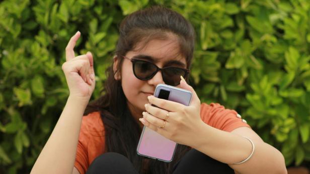 Mädchen mit Sonnenbrille hat Handy in der Hand