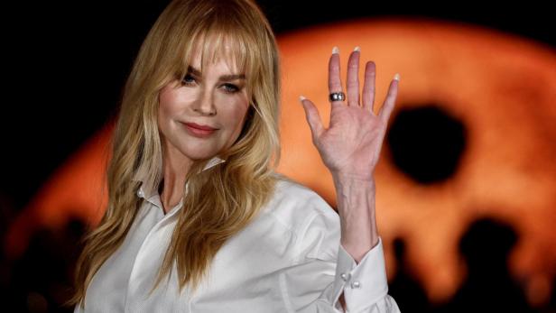 Nicole Kidman trägt ein weißes Hemd und winkt in die Kamera.