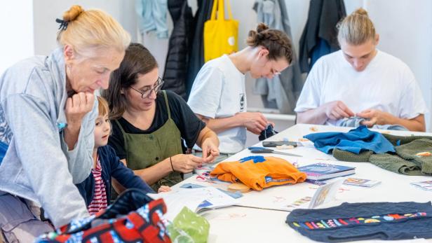 Vier Personen mit Nähsachen auf einem Tisch
